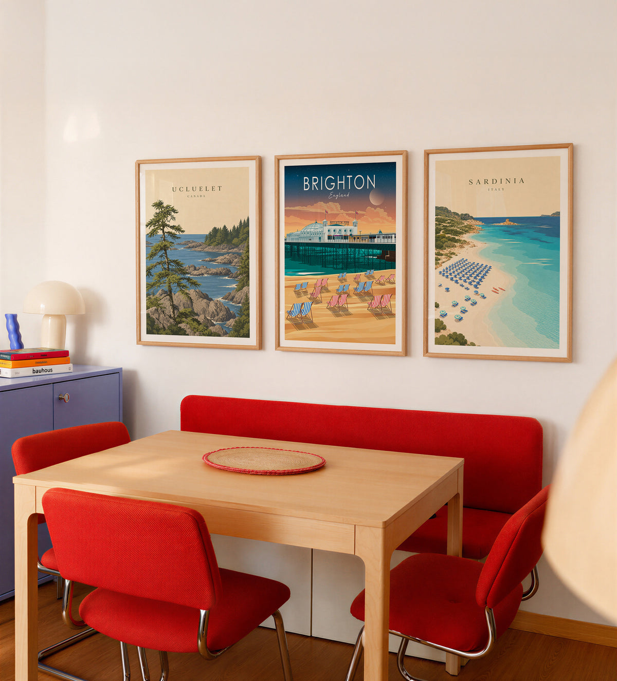 Three framed travel posters above a dining table with red chairs